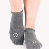 Women wearing gray grip socks with white smiley face for Pilates, Barre, Yoga, and beyond. 