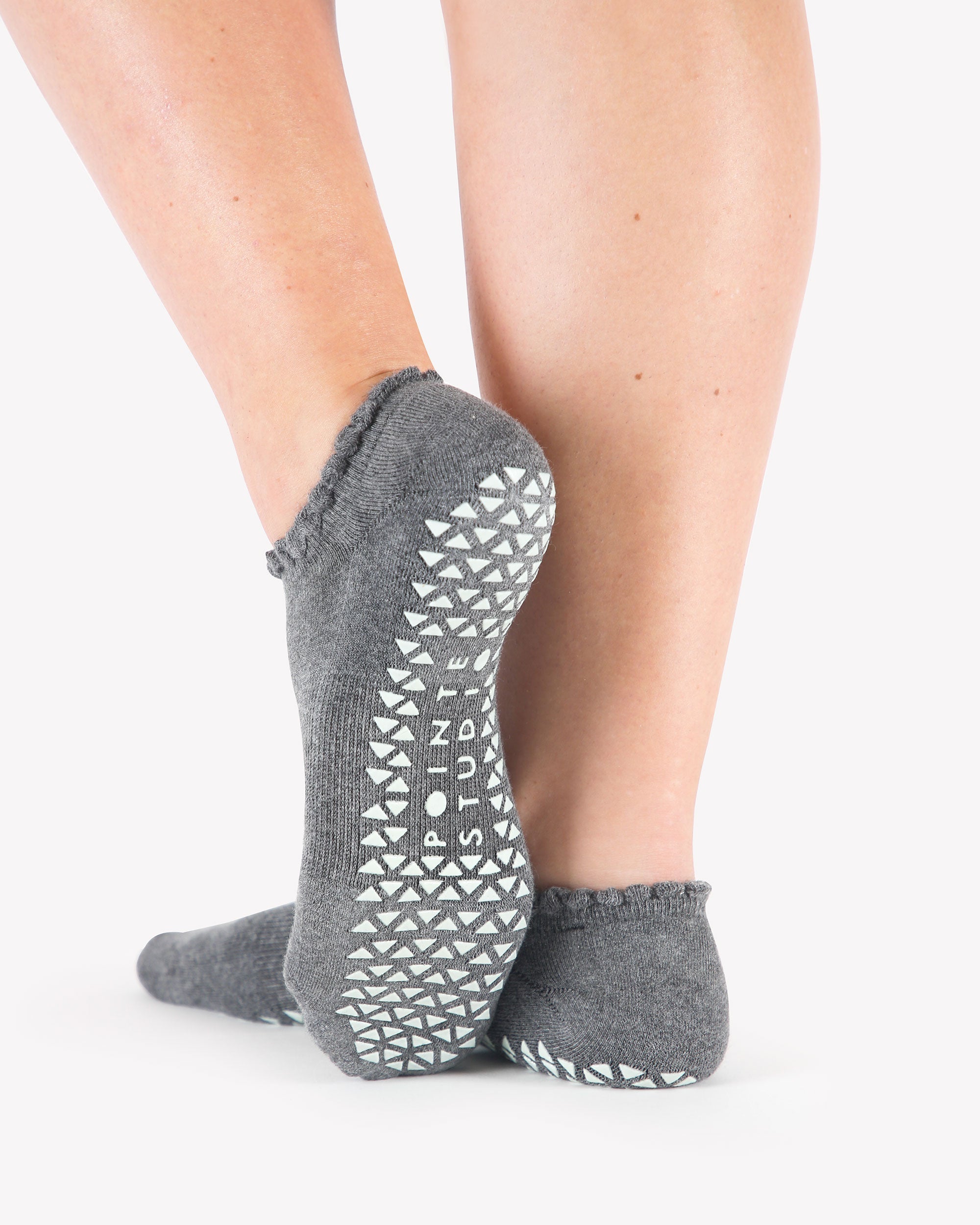 Women wearing gray grip socks with white smiley face for Pilates, Barre, Yoga, and beyond. 
