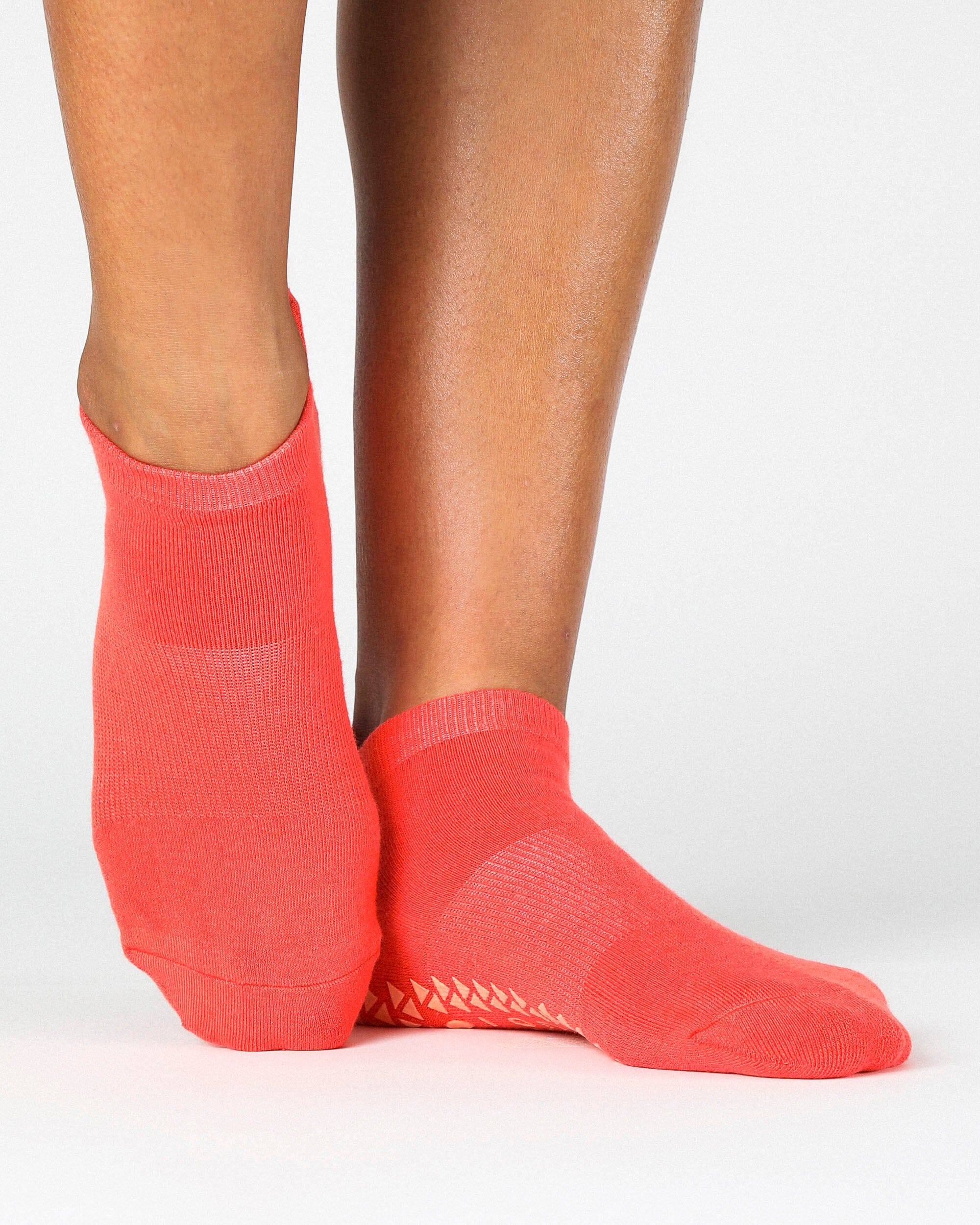 Women wearing a solid hot coral full foot grip sock made for Pilates, Barre, Yoga, and beyond. 