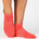 Women wearing a solid hot coral full foot grip sock made for Pilates, Barre, Yoga, and beyond. 