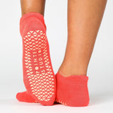 Women wearing a solid hot coral full foot grip sock made for Pilates, Barre, Yoga, and beyond. 