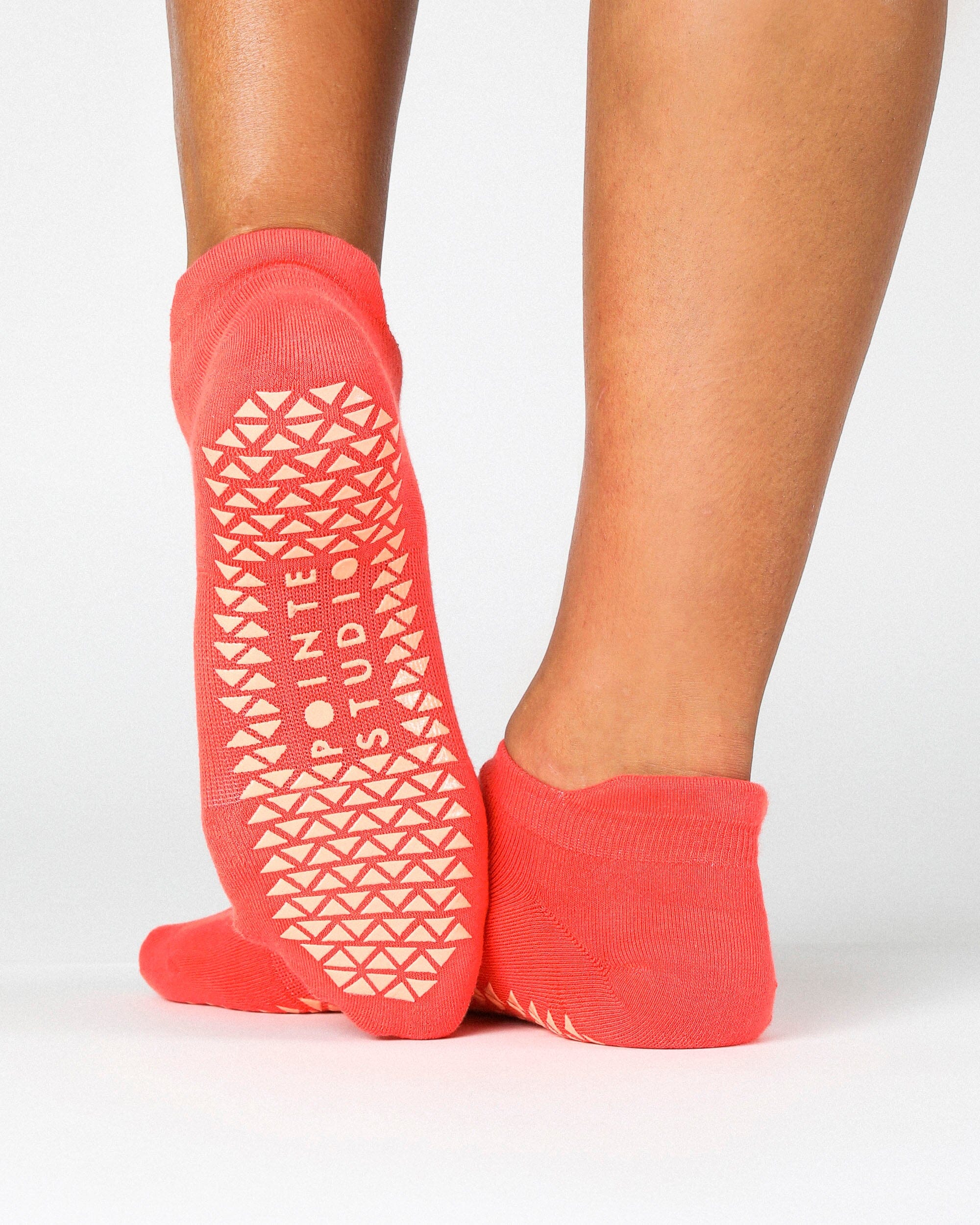 Women wearing a solid hot coral full foot grip sock made for Pilates, Barre, Yoga, and beyond. 