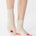 Women wearing a off white ankle grip sock with a red heart motif on the top made for Pilates, Barre, Yoga, and beyond. 