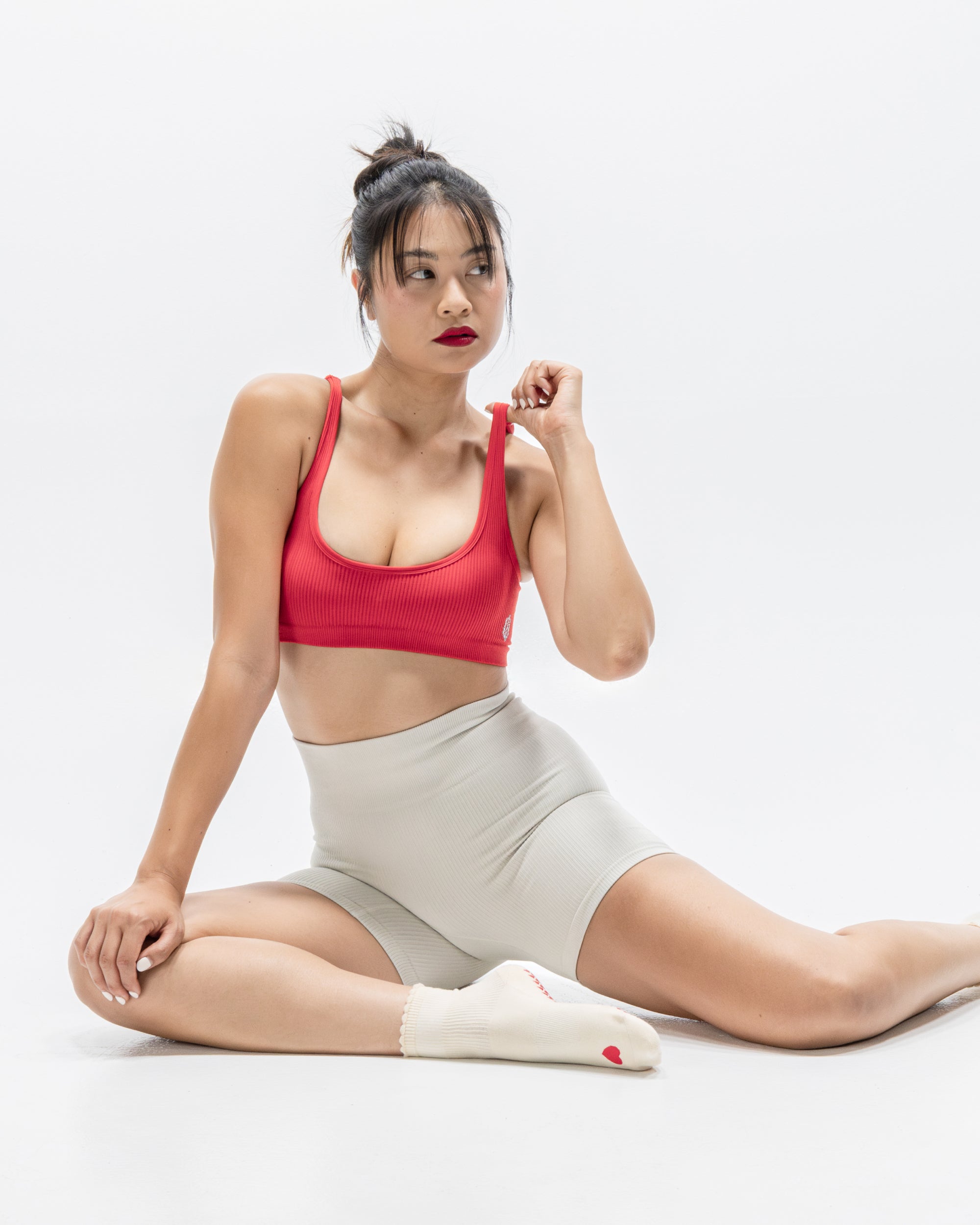 Women wearing a off white ankle grip sock with a red heart motif on the top made for Pilates, Barre, Yoga, and beyond. 