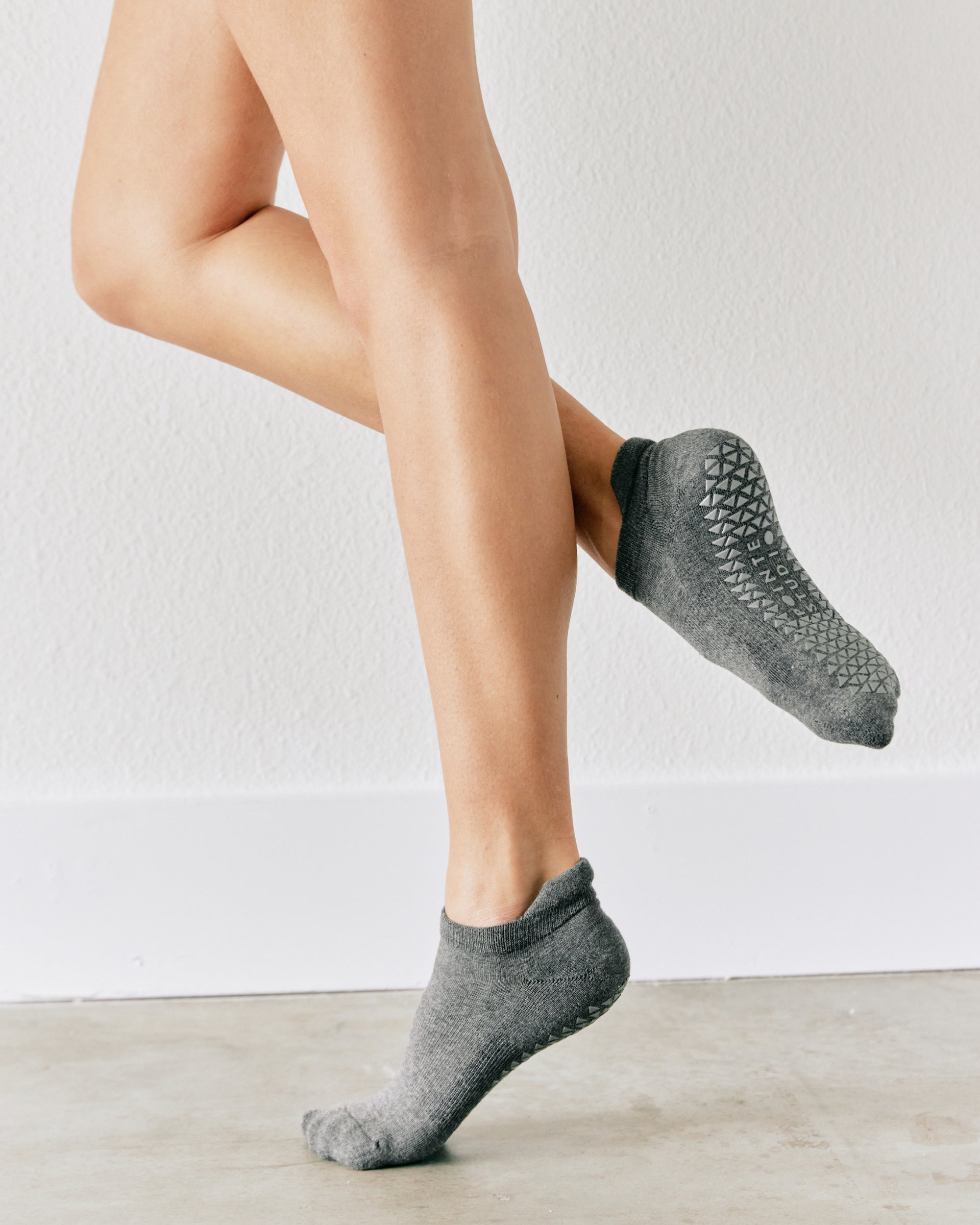 Women wearing a solid gray full foot grip sock made for Pilates, Barre, Yoga, and beyond. 