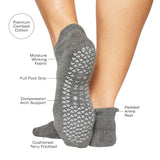 Women wearing a solid gray full foot grip sock made for Pilates, Barre, Yoga, and beyond with the features listed.