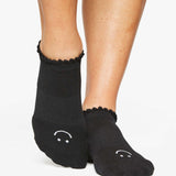 Close up photo of a woman's feet wearing black socks with a happy face on the top of the foot