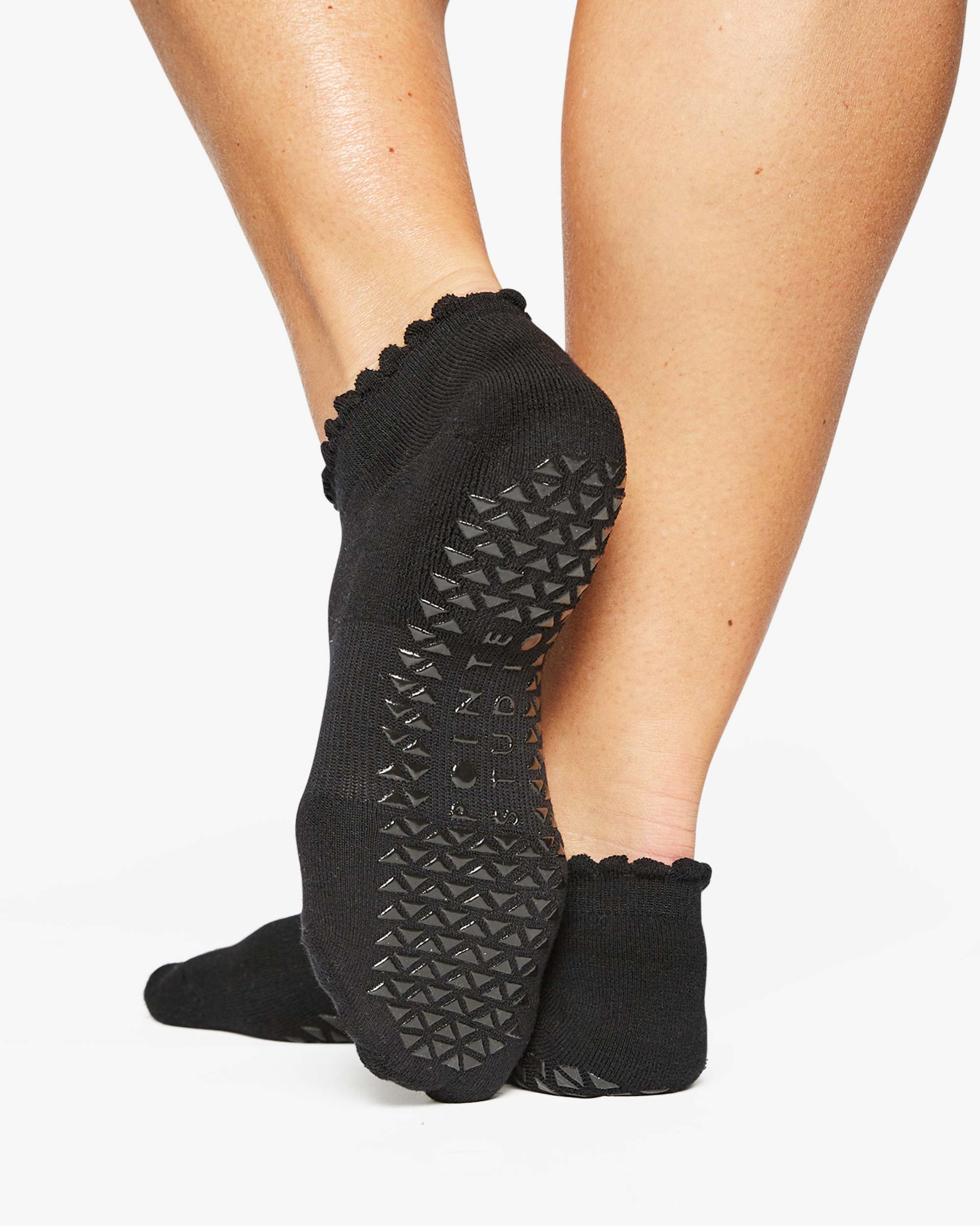 Close up photo of a woman's feet wearing black socks with grip of the bottom of the foot
