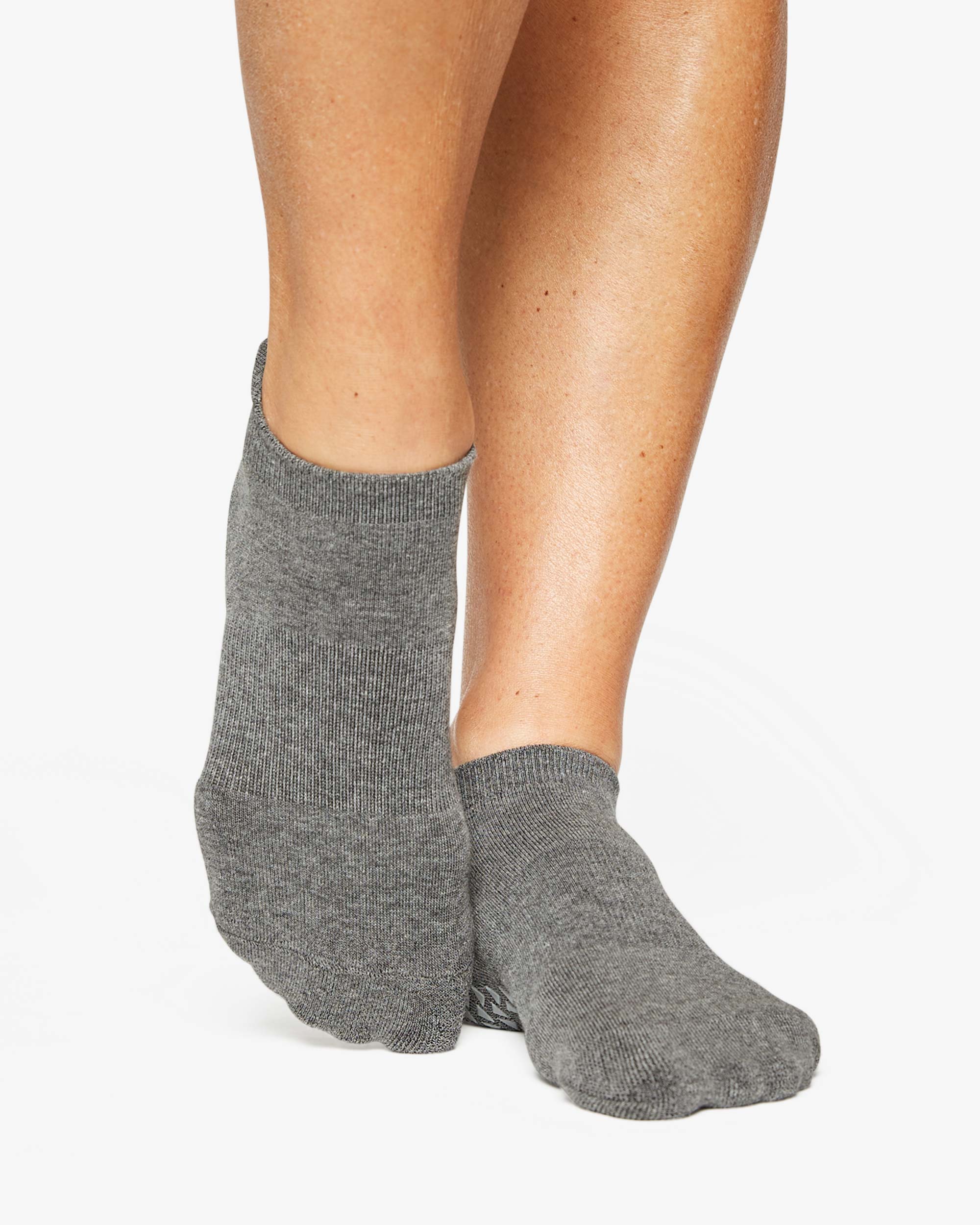 Women wearing a solid gray full foot grip sock made for Pilates, Barre, Yoga, and beyond. 