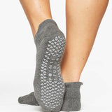 Women wearing a solid gray full foot grip sock made for Pilates, Barre, Yoga, and beyond. 